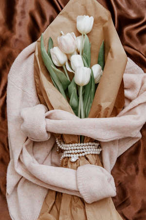 Bouquet of white tulips on a knitted sweater, top view, bouquet of tulips for women's day, concept of spring flowers. Cozy soft backgroundの写真素材