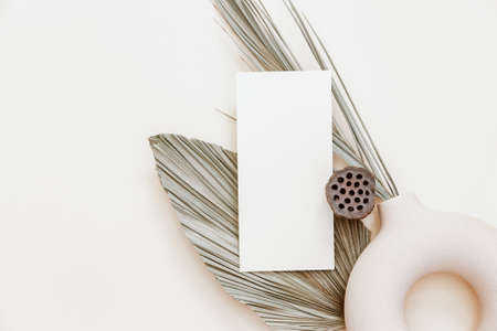 Minimal Summer stationery still life scene. Mock up with blank card and tropical palm leaf on beige...