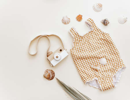Summer concept for kids, cute retro baby swimsuit with wooden camera and palm leaf, holiday child backgroundの写真素材