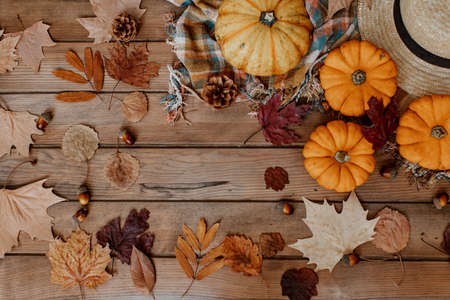 Flat Lay Autumn background decoration from dry leaves, straw hat and pumpkin on wooden background. Top view for Autumn, fall, Thanksgiving concept.の写真素材