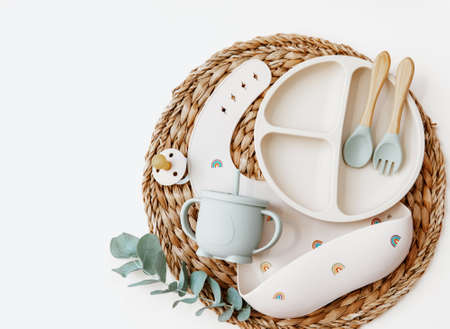 Flat lay Baby food accessories. silicone bib, fork and spoon on light background.の写真素材