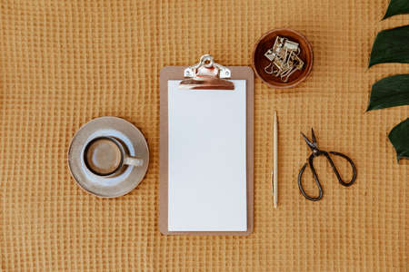 Wooden office desk table with clipboard, supplies. Blank notebook page for text. Minimal blogger background. Planning or goals.の写真素材