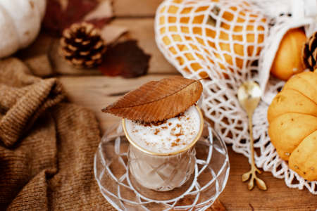 Autumn art composition - hot drink, varied dried leaves, pumpkins on wooden background, cozy autumnの写真素材