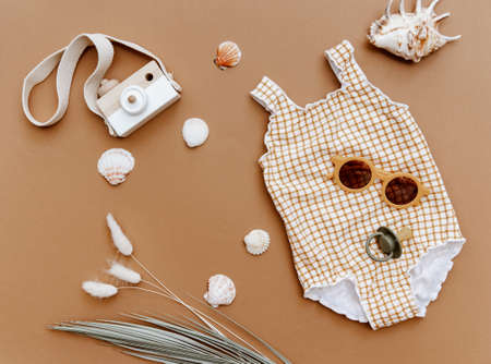 Flat lay retro vintage swimsuit for baby girl on brown background. Minimal summer conceptの写真素材