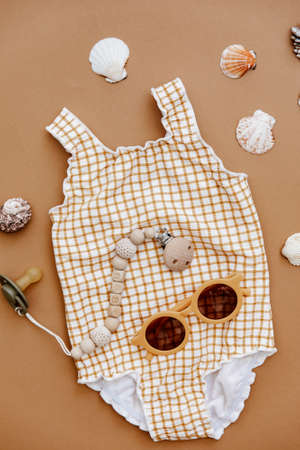 Vintage swimsuit for child with sunglasses on brown background. Summer kid's vacation concept. Top view, flat layの写真素材