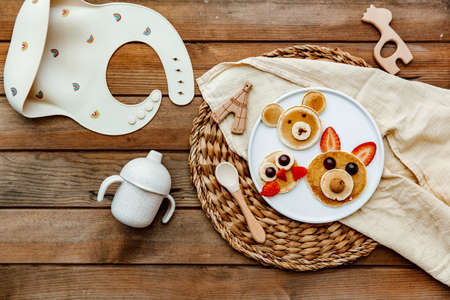 Pancakes With Funny Faces Decorated For Kids. Healthy Fruit Pancakes For baby Meal over wooden background, top viewの写真素材