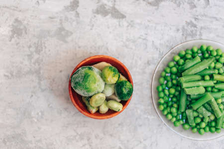 Frozen Brussels sprouts green cabbage on kitchen table. White background.