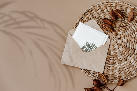 Flat Lay Aesthetic background with envelope and dry floral branch on beige background. Wedding invitation template. top view, mock up, copy spaceの写真素材