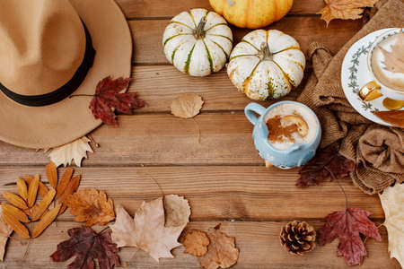 Autumn fall composition. Wooden desk table with knitted sweater, hot coffee, hat and pumpkin. Flat lay, top view. Nordic, hygge, cozy home conceptの写真素材
