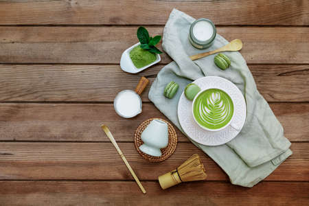 Green matcha tea in a white cup, tea powder and wooden spoon. Healthy drinks. Top view, flat lay.の写真素材