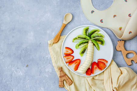 Creative meal for a child, strawberries and banana, funny food over wooden background. Fruits for baby. Top view, flat layの写真素材