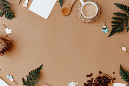 Top view brown neutral workspace office desk with coffee and office supplies. Flat lay work table with craft notebook, green olive leaf and supplies. Home bloggerの写真素材