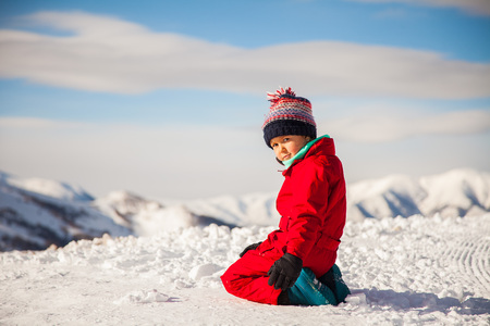 Portrait of happy little girl with sunglasses enjoy ski outdoor. Active sportive girl in ski gear on winter mountains on background. Smiling cute girl has fun in snow.の写真素材