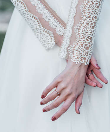 brides hand with an elegant wedding ring with white gold diamonds on a bouquet of their peoniesの写真素材