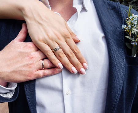 brides hand with an elegant wedding ring with white gold diamonds on a bouquet of their peoniesの写真素材