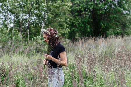 young woman with a wreath of daisies on her head in the sun on a field of grass