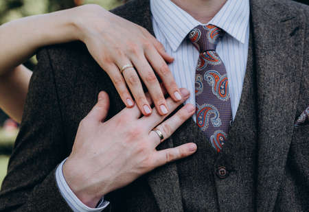 brides hand with an elegant wedding ring with white gold diamonds on a bouquet of their peoniesの写真素材