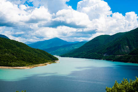 mountain lake with blue turquoise clear water against the backdrop of a clear sky and mountain hillsの写真素材
