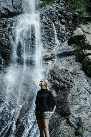 young woman on the background of a mountain waterfall with a ponytailの写真素材