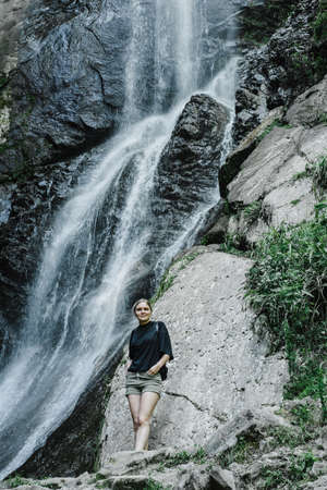young woman on the background of a mountain waterfall with a ponytailの写真素材