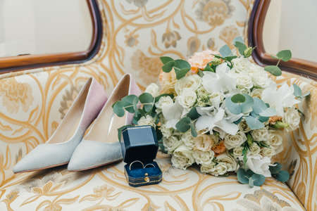 white gold wedding rings in a box and a bridal bouquet of delicate roses and greenery