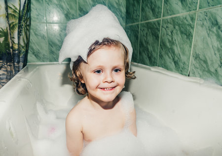 beautiful child toddler son washes in the bathroom plays has fun with soap bubbles,foam