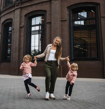 young beautiful mother with long hair with children on walk in street happiness joy fun motherhoodの写真素材