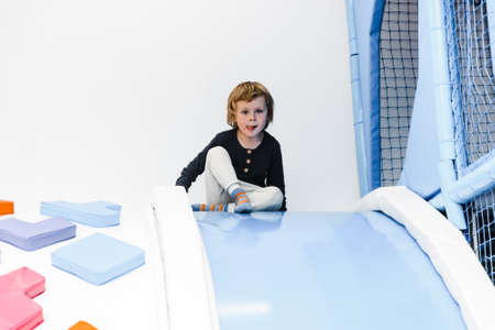 child boy son plays in the childrens room with inflatable trampolines, climbs the slide active game...