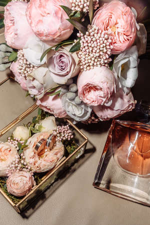 wedding gold rings in a glass box lie next to a wedding bouquet with austom. aesthetics and details...