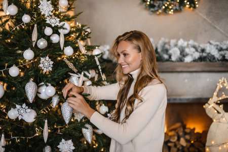 young beautiful woman model with long hair in a beige suit christmas tree christmas In brown wooden housesの写真素材