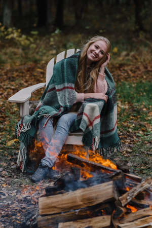 young woman sitting by the fire in colored warm ice warming up fire heat long hairの写真素材