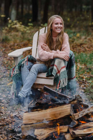 young woman sitting by the fire in colored warm ice warming up fire heat long hairの写真素材
