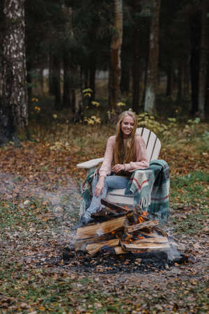 young woman sitting by the fire in colored warm ice warming up fire heat long hairの写真素材