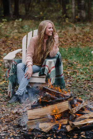 young woman sitting by the fire in colored warm ice warming up fire heat long hairの写真素材