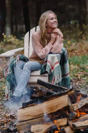 young woman sitting by the fire in colored warm ice warming up fire heat long hairの写真素材