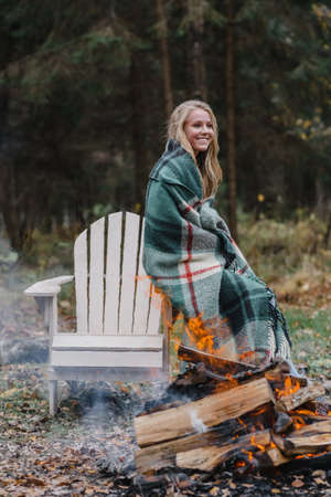 young woman sitting by the fire in colored warm ice warming up fire heat long hairの写真素材