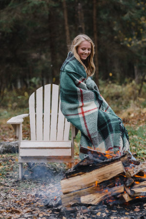 young woman sitting by the fire in colored warm ice warming up fire heat long hairの写真素材