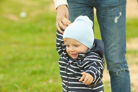 Single mother carrying and hugging a child outdoors near lake with natural yellow and white...