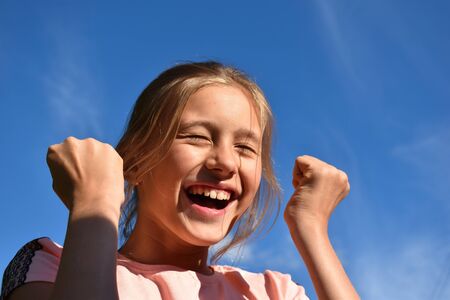 Beautiful little girl on background of clear blue sky in the summer.Dear child rejoices with all  heart.の写真素材