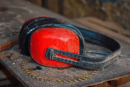 Red noise-protective earphones of wood working carver. Carpenter's workshop with slips. Desktop of the joiner. Noise.の写真素材