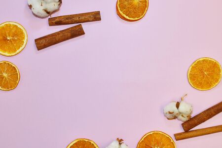Pink wallpaper with decorative floral elements. Slices of dry orange, cinnamon on pink