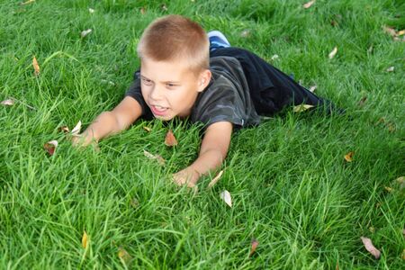 The child wallows in the green grass in the summer.の写真素材