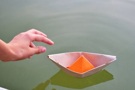 Cardboard ships in a fountain in a city park. Children's natural paper toys.