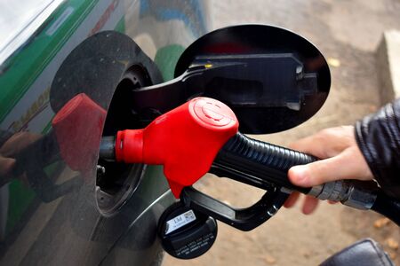 The machine at the gas station refuel. A man's hand holds a gasoline gun.