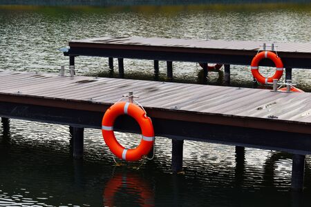 Lake in a city park with a wooden pier for boats. Cozy water natural landscape. A haven for small pleasure boats.の写真素材