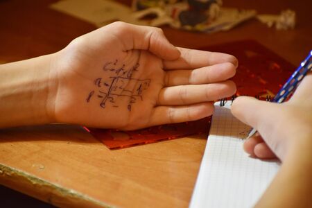 The student peeps on the exam. Cheating in the lesson. Crib in school.