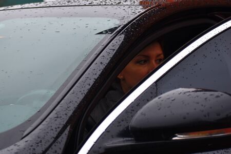 Face of beautiful woman in a car. Woman opened door to the car in rain.
