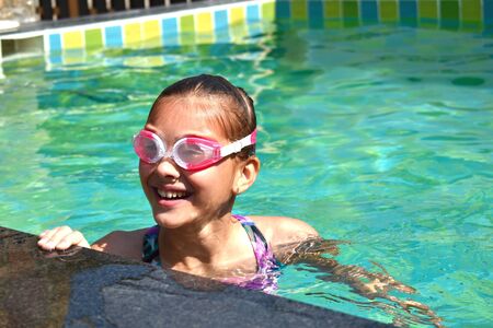 Happy childhood on the water. Young girl child in water glasses.の写真素材
