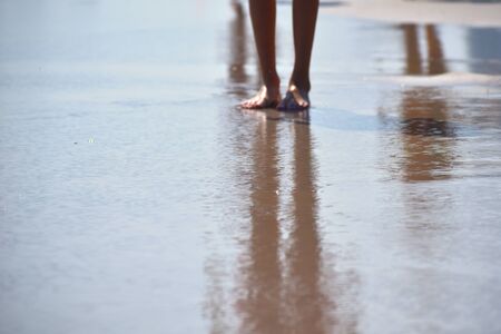 Feet along the line of the ocean. Sea vacation concept. Children's vacation at sea.の写真素材