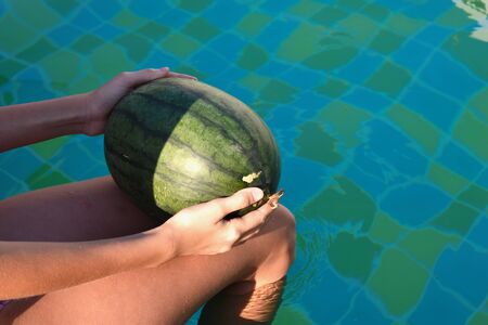 Girl playing with a green watermelon. Happy children's vacation in the tropics.の写真素材
